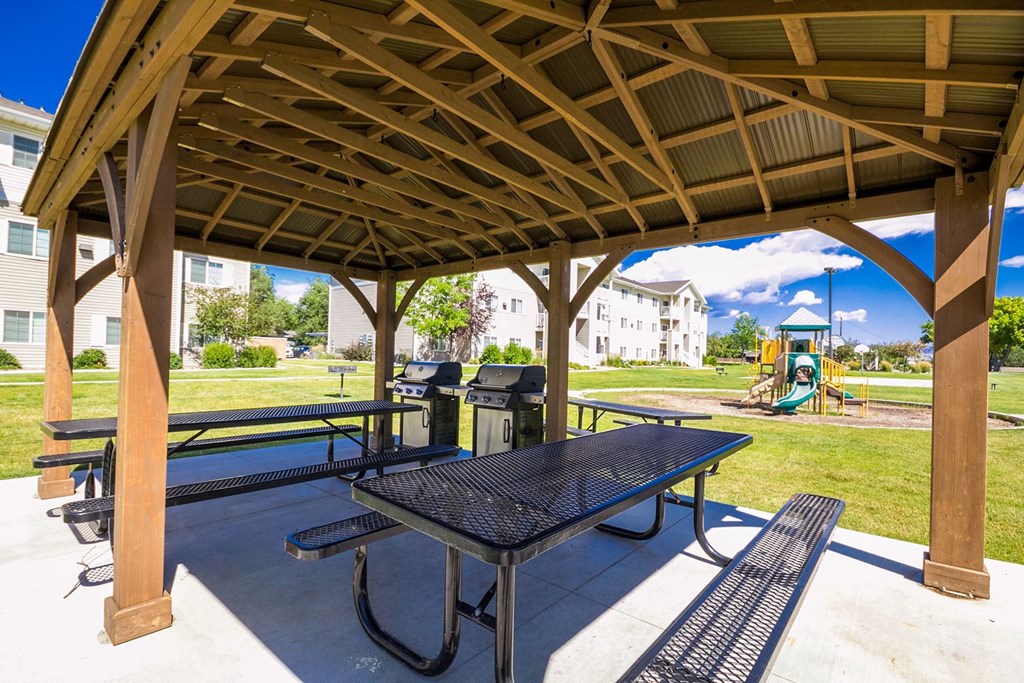 A wooden pavilion with a black table and benches.
