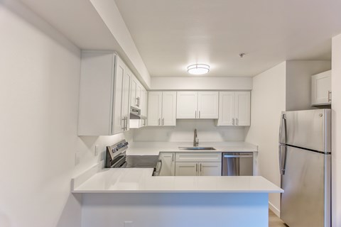 A white kitchen with a refrigerator on the right.