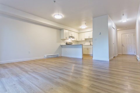 A spacious room with wooden flooring and white walls.