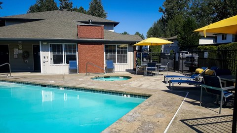 A pool area with a building and patio furniture.
