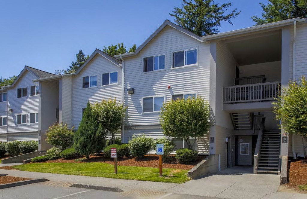 a white apartment building with a sidewalk and trees