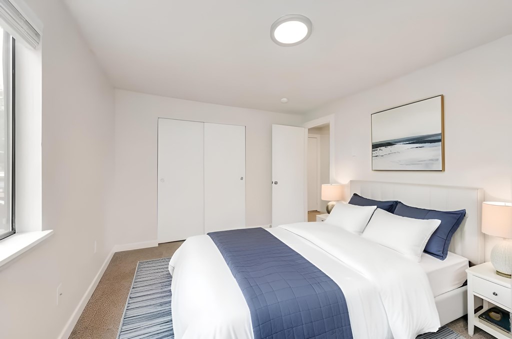 A bedroom with a large bed and a picture on the wall.