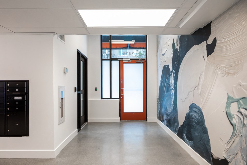 a hallway with a mural on the wall and a red door