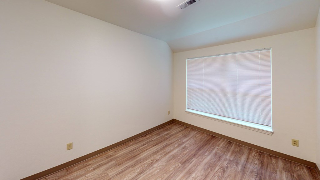 an empty room with wood floors and a large window