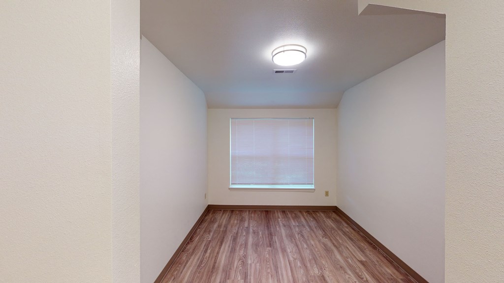 an empty room with wood floors and a window