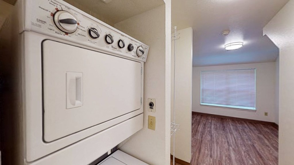 a white washer and dryer in an empty kitchen with a window and a