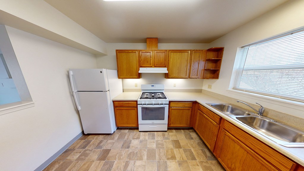 a kitchen with wooden cabinets and a refrigerator and a sink