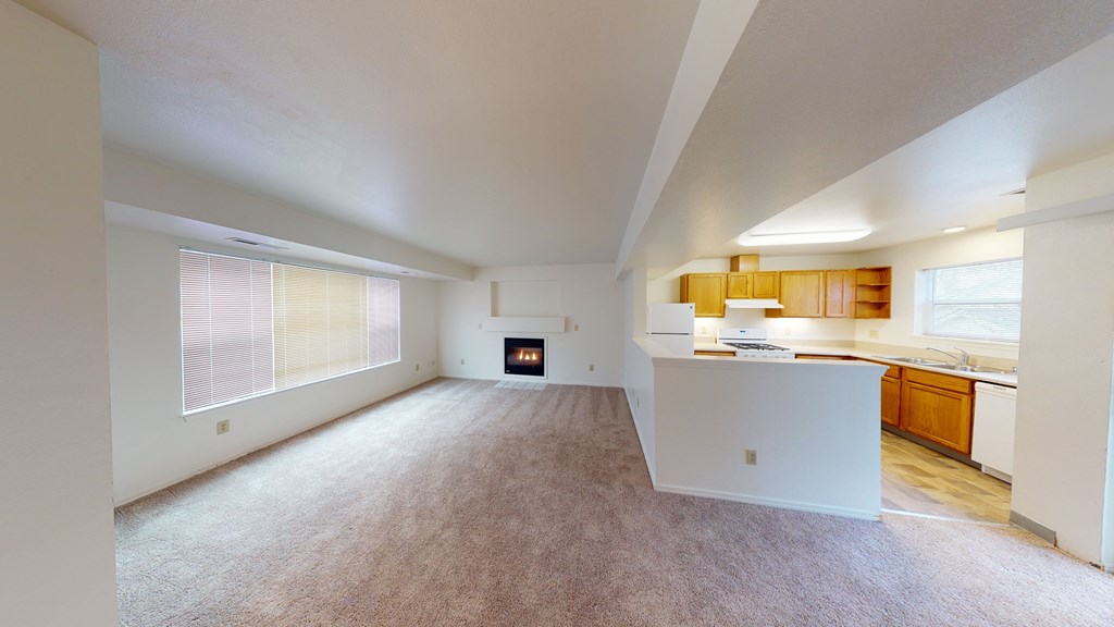 an empty living room and kitchen with a fireplace