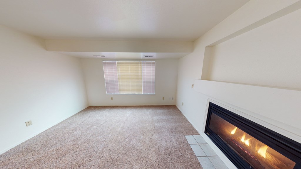 an empty living room with a fireplace and a window