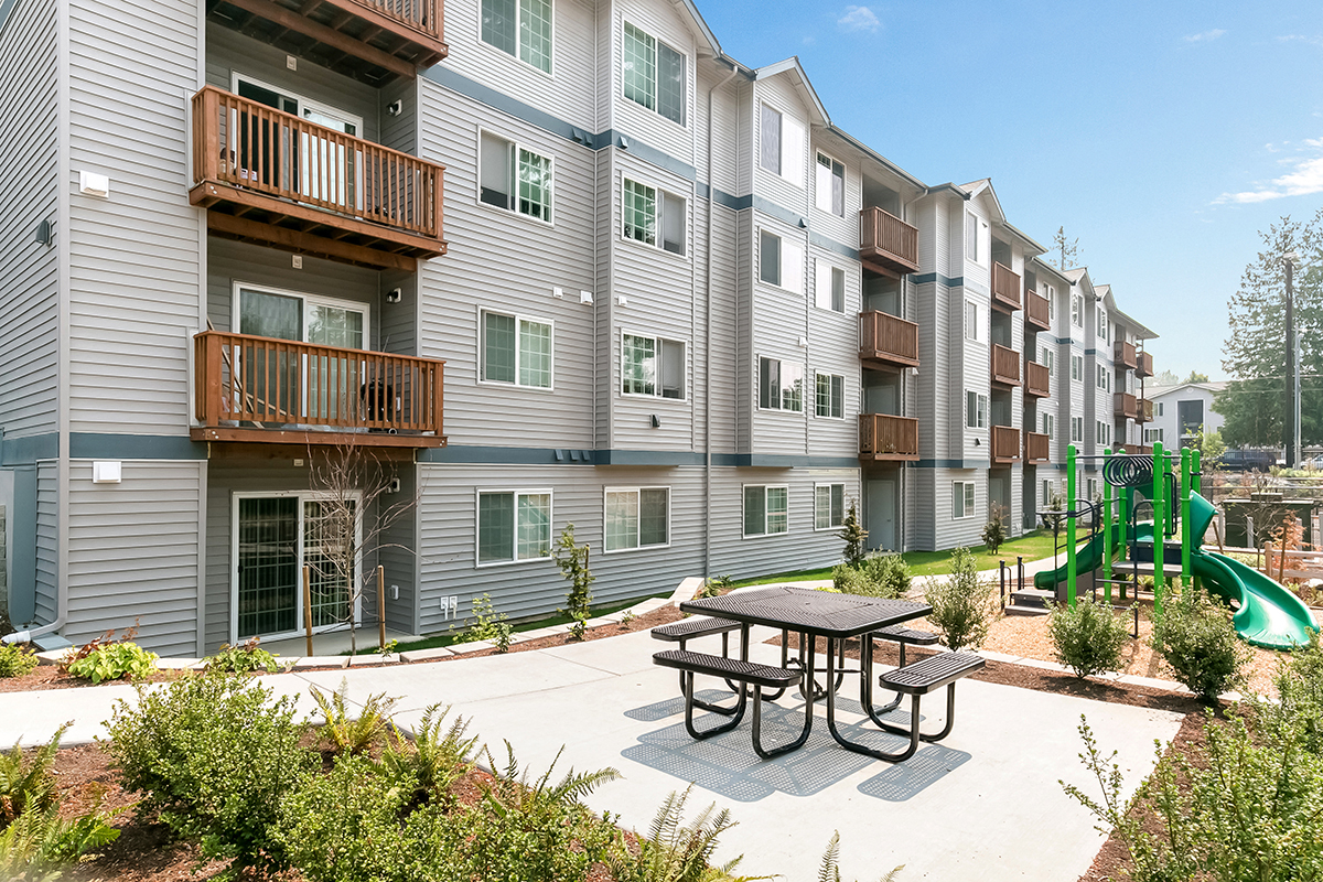 an outdoor patio with a picnic table and playground at an apartment building