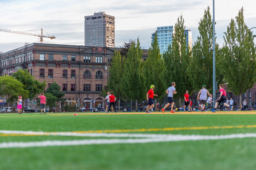 a group of people running on a soccer field in a city