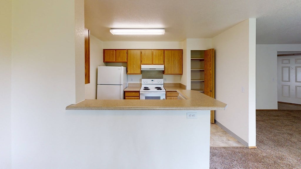 an empty kitchen with a counter top and a white refrigerator