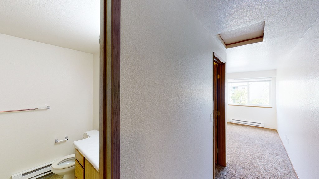 an empty bathroom with a toilet and a window