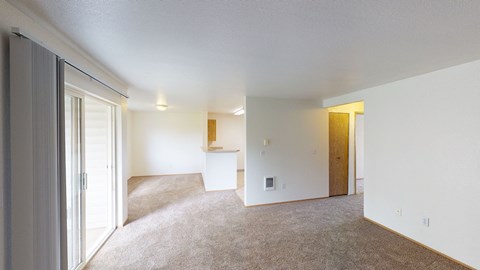 the living room and dining room of an apartment with white walls and carpet