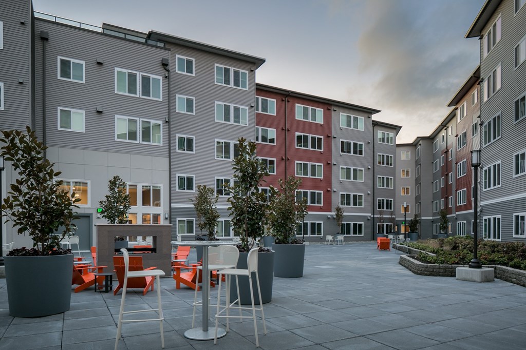 an open courtyard with tables and chairs in front of an apartment building