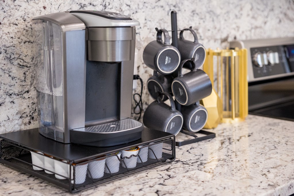 A coffee machine and a set of mugs are on a counter.