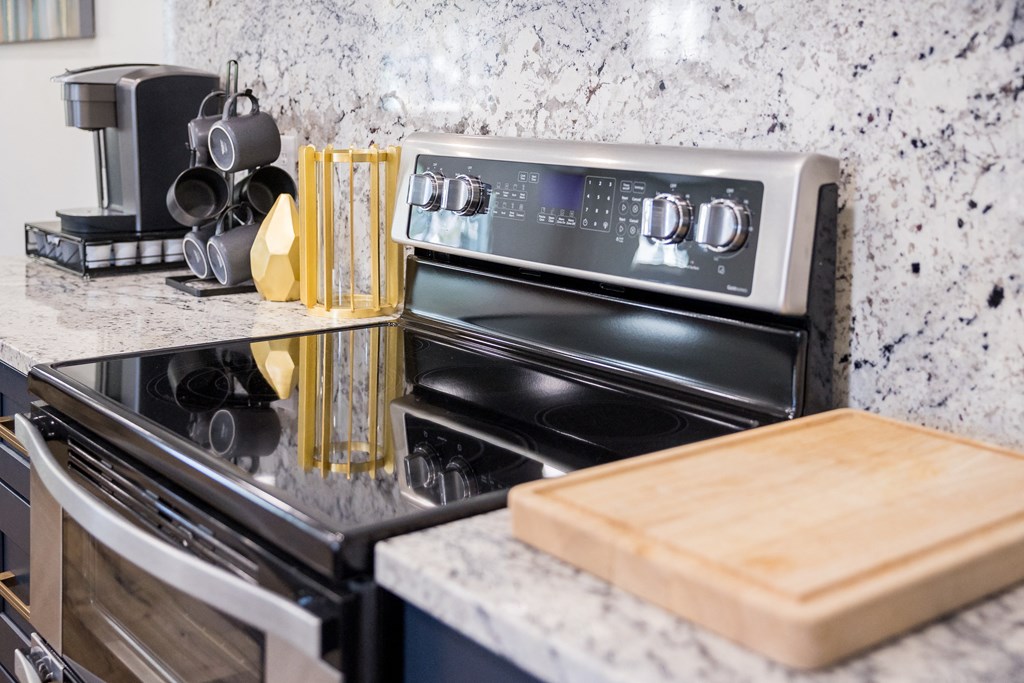 A modern kitchen with a black stove top oven and a wooden cutting board.