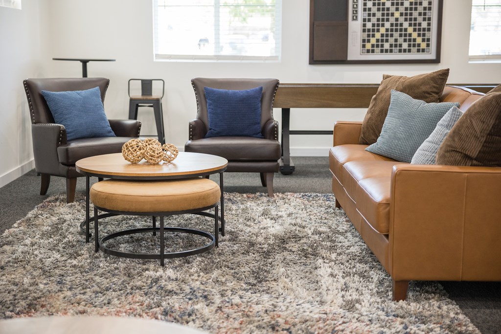 A living room with a brown couch, a coffee table, and two chairs.