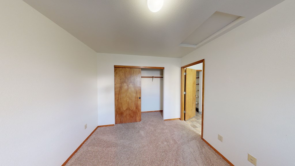 a living room with carpet and a door to a bedroom