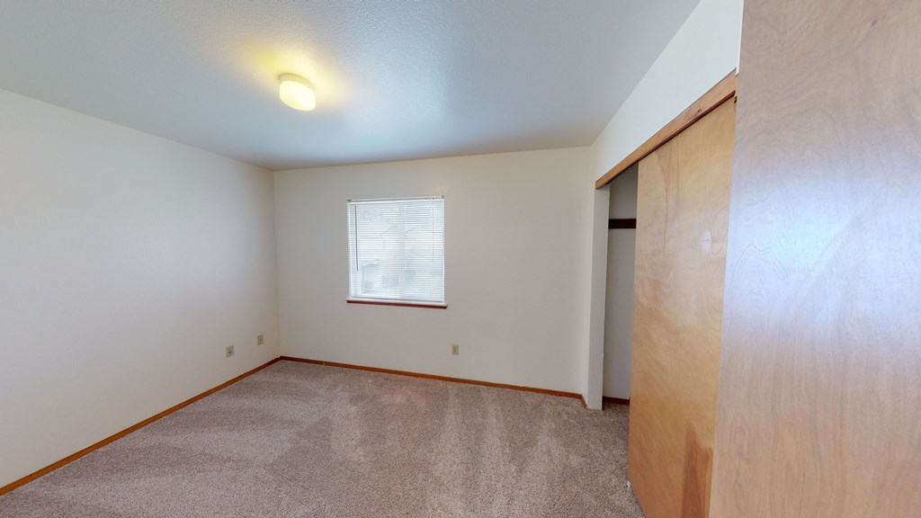 the living room of an empty home with a door to a closet