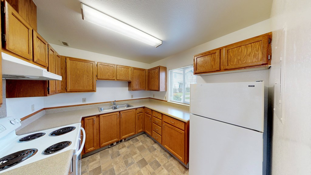 an empty kitchen with white appliances and wooden cabinets