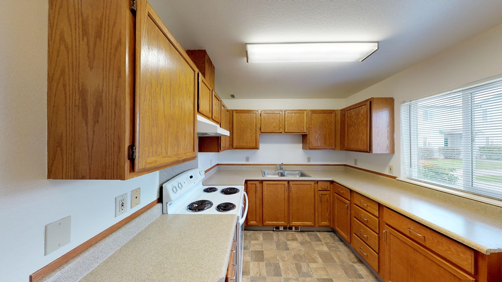 an empty kitchen with wooden cabinets and white counter tops