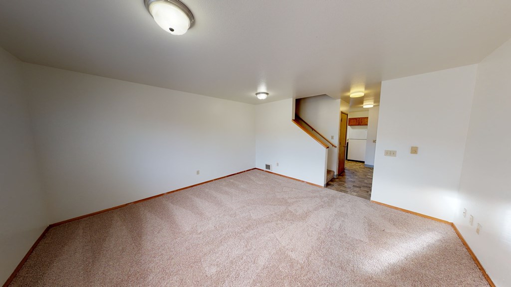 a spacious living room with carpet and white walls
