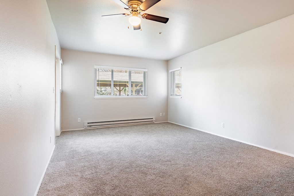 an empty room with a ceiling fan and a window