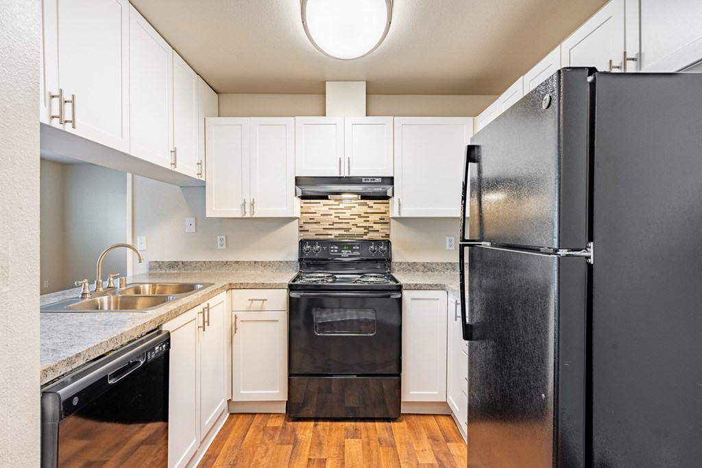 a kitchen with white cabinets and black appliances