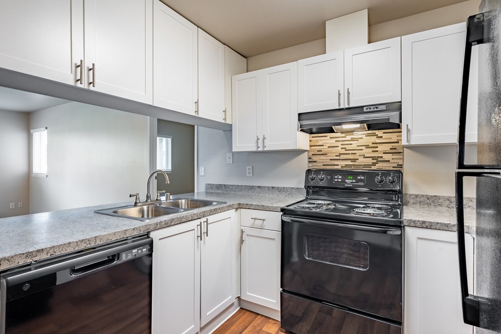 a kitchen with white cabinets and black appliances