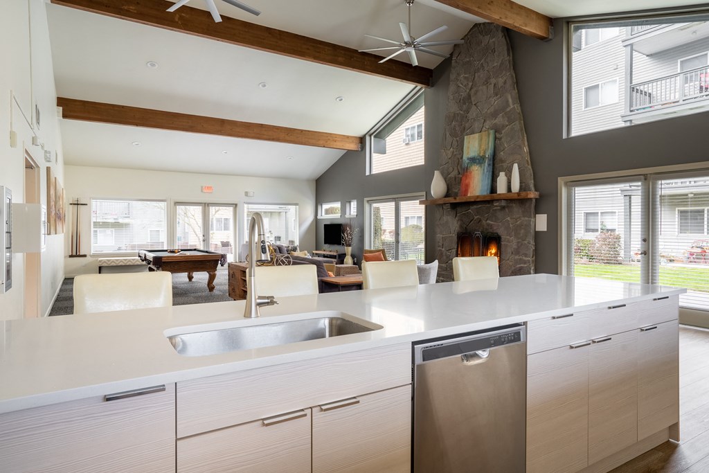 a kitchen with a large center island next to a living room with a pool table and a