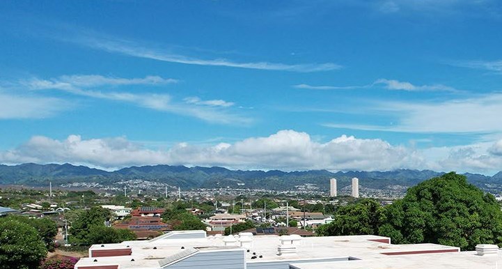 A blue and red building with a white roof and a green lawn in front.