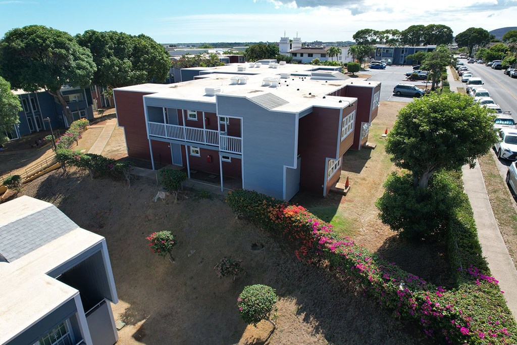 A building with a red and white exterior is surrounded by a parking lot and greenery.