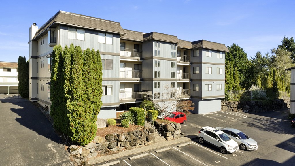 an aerial view of an apartment building in a parking lot with cars