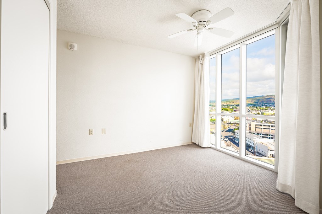 a bedroom with a large window and a ceiling fan