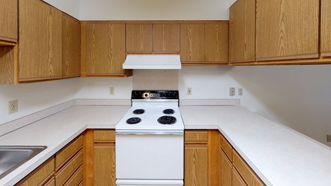 an empty kitchen with white appliances and wooden cabinets