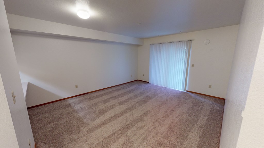 an empty living room with carpet and a sliding glass door