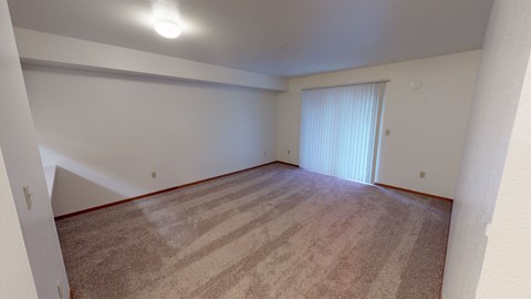 an empty living room with carpet and a sliding glass door