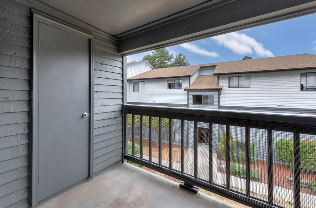 A balcony with a black railing and a grey door.