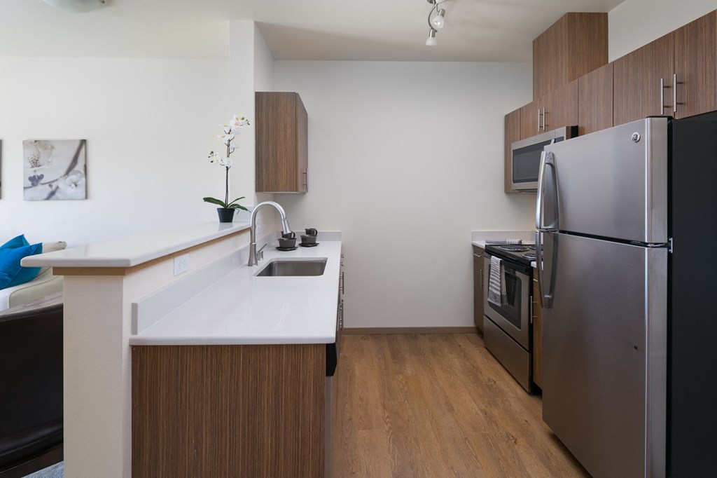 a kitchen with a white counter top and a stainless steel refrigerator