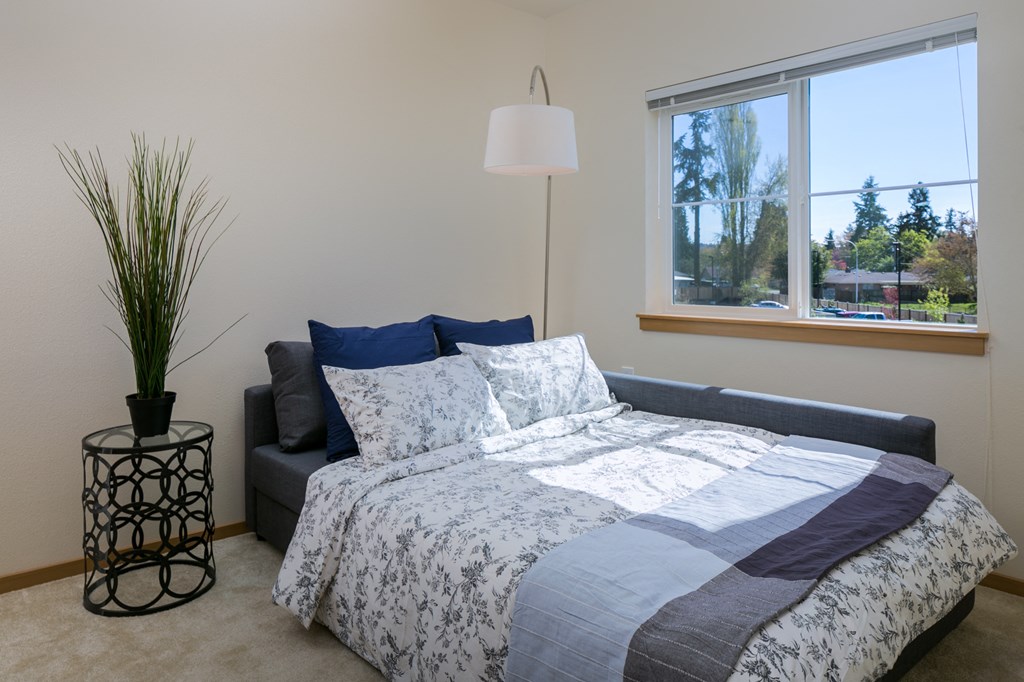 a bedroom with a bed and a lamp and a window