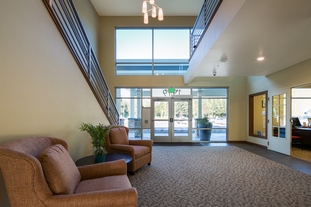 a lobby with couches and chairs in front of a glass door