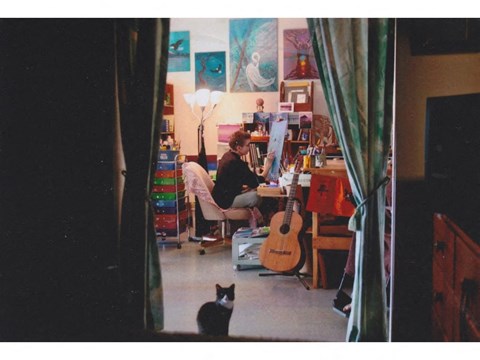 a woman sitting at a desk with a cat in the foreground