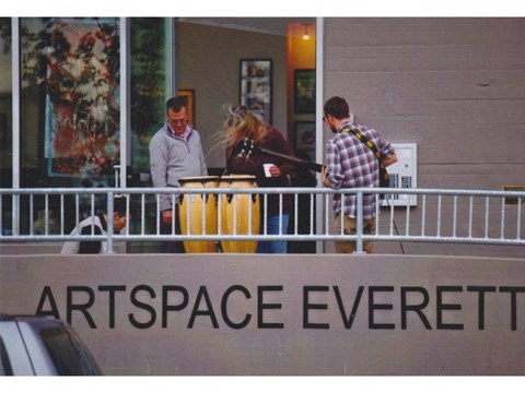 A group of people are standing on a balcony with a sign that says "ARTSPACE EVERETT".