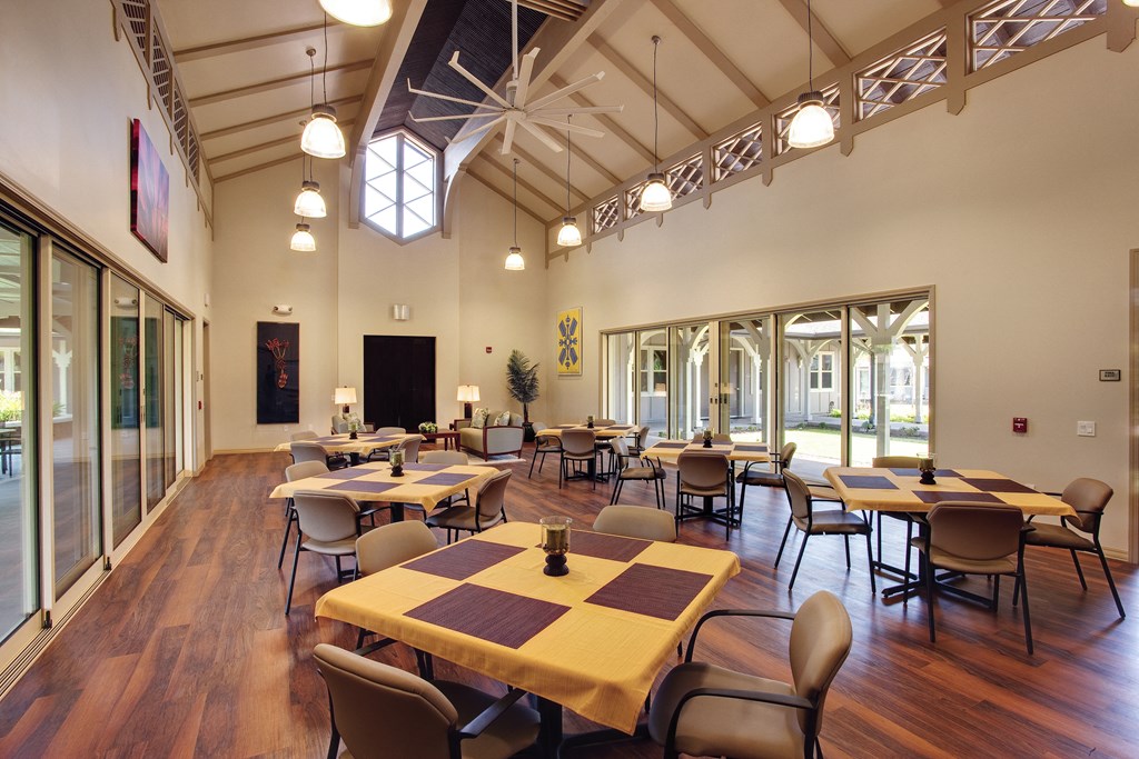 a dining room with tables and chairs in a hall with large windows