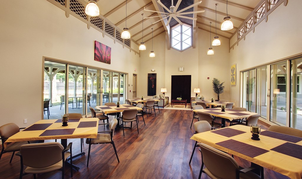 a dining room with tables and chairs in a large room with windows