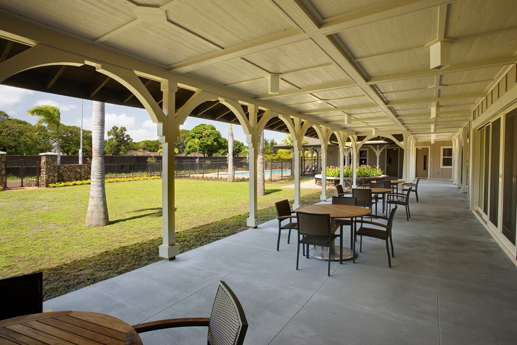 a patio with tables and chairs and a grass field