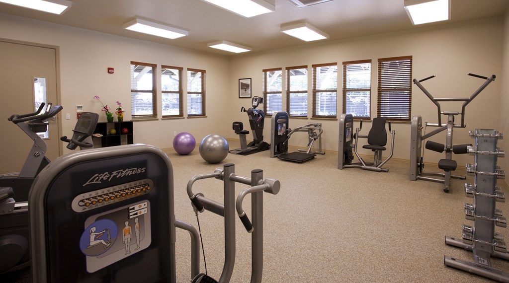 a gym with various exercise equipment in a room with windows