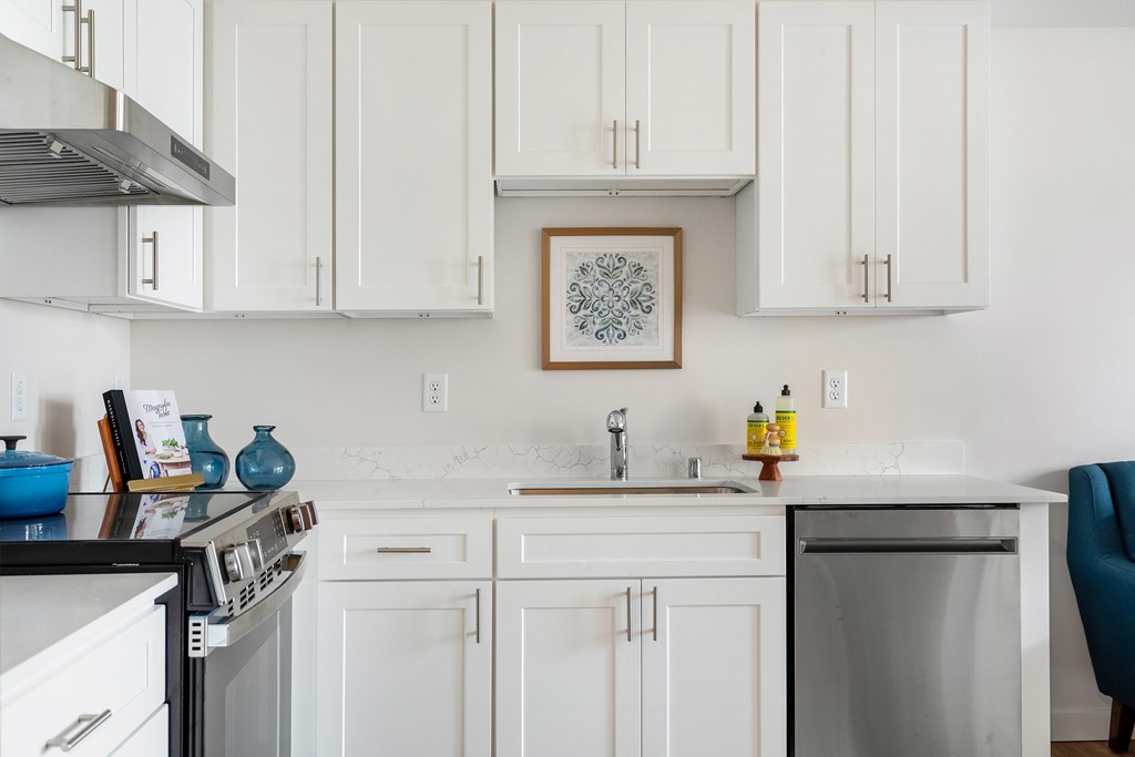 A kitchen with white cabinets and a framed picture hanging on the wall.