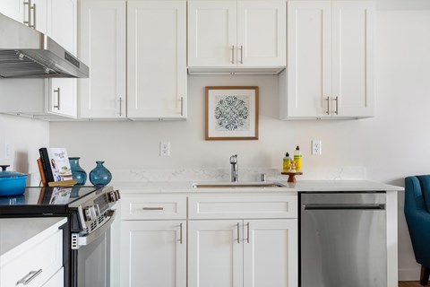 A kitchen with white cabinets and a framed picture hanging on the wall.